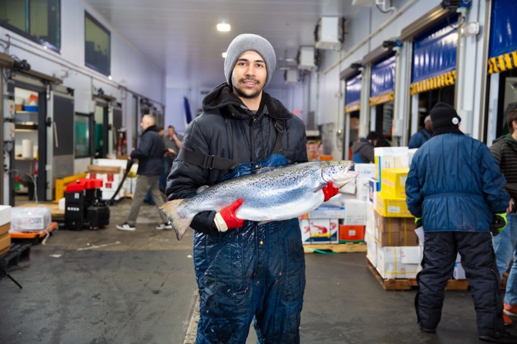 Ocean Seafood Depot worker holding a fresh salmon before delivery to restaurant